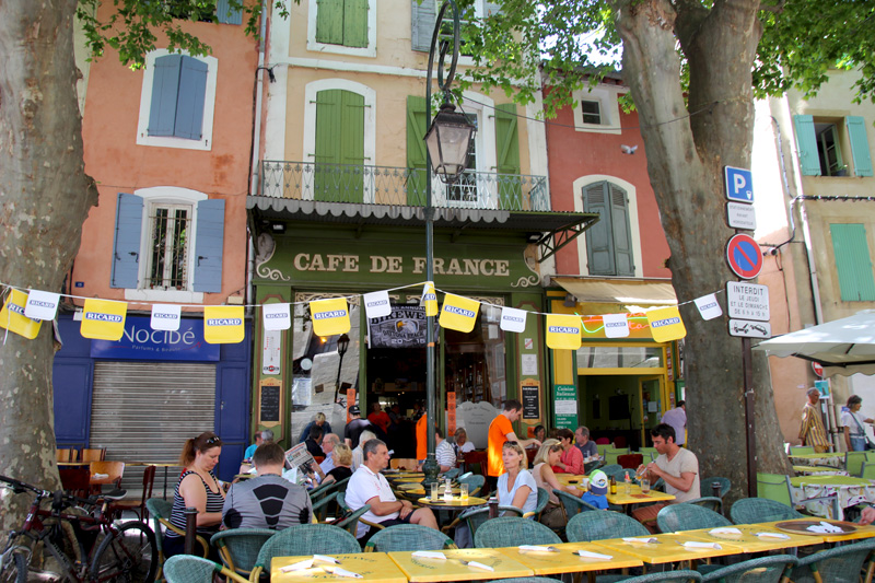 People sitting outside a cafe in France, plane trees give shade