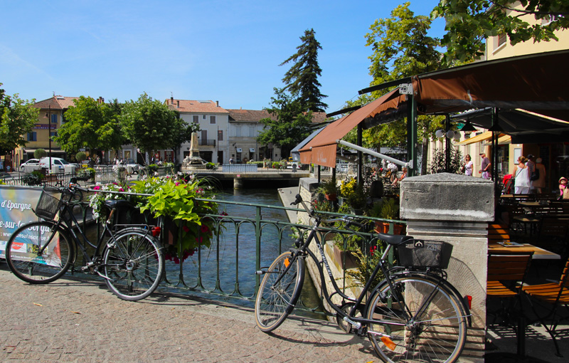 Bikes along a river on a sunny day in the town of Isle-sur-la-Sorgue, Provence