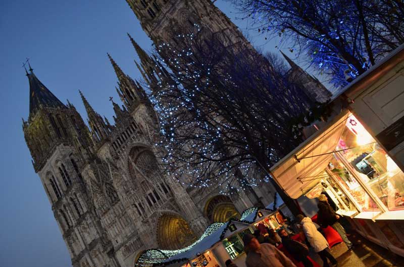 The Cathedral of Rouen looming over the Christmas market, trees with twinkling lights