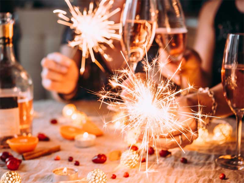People clinking glasses of wine and holding sparklers